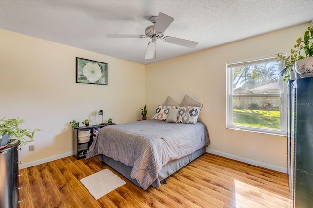 bedroom featuring a textured ceiling, wood finished floors, and baseboards