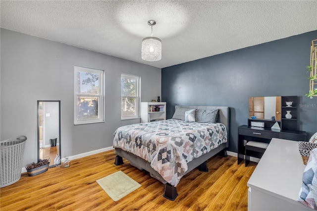 bedroom with a textured ceiling, wood finished floors, and baseboards