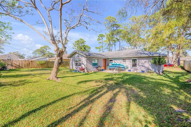 back of house with a fenced backyard, a lawn, and a patio