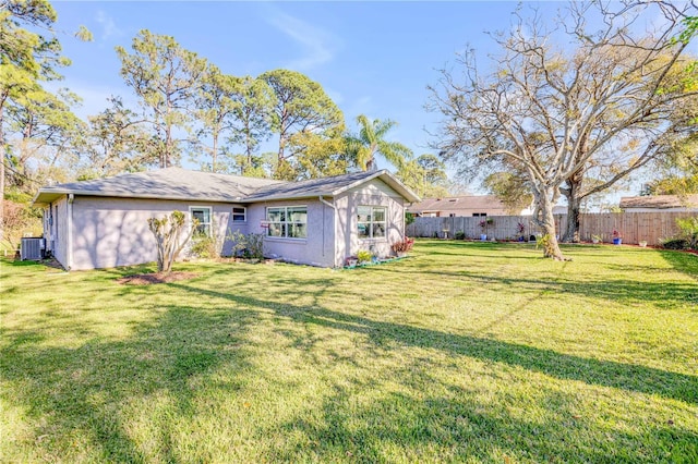 back of house featuring a yard, stucco siding, cooling unit, and fence