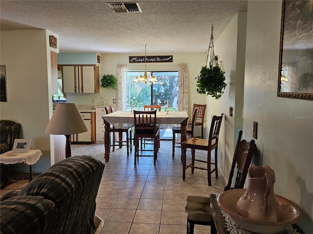 dining room featuring an inviting chandelier, visible vents, a textured ceiling, and light tile patterned flooring