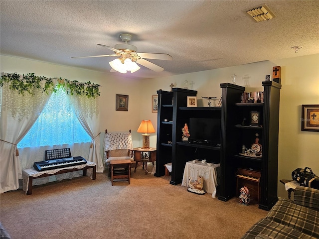 living area featuring ceiling fan, a textured ceiling, carpet, and visible vents