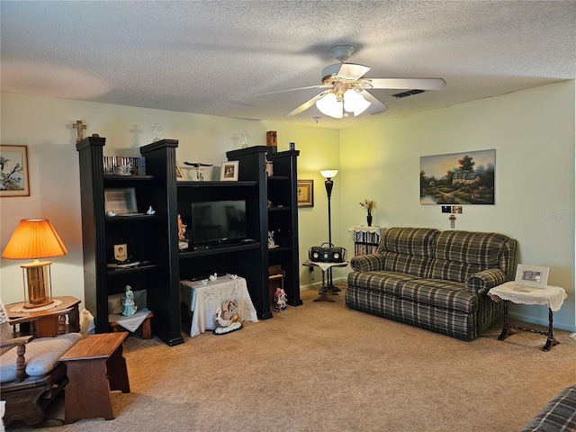 living area with baseboards, visible vents, ceiling fan, a textured ceiling, and carpet flooring