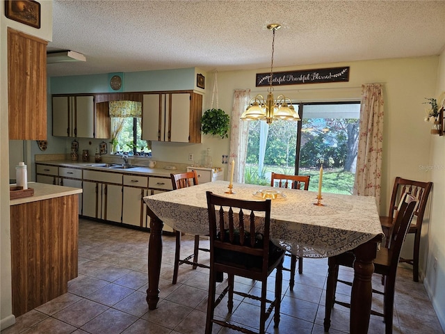 dining area with a chandelier, dark tile patterned floors, and a textured ceiling