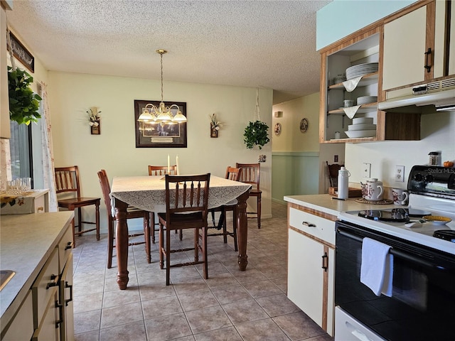 kitchen with decorative light fixtures, light countertops, under cabinet range hood, and electric range oven