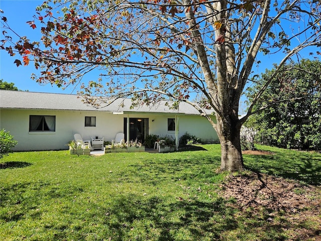 rear view of property with stucco siding and a yard