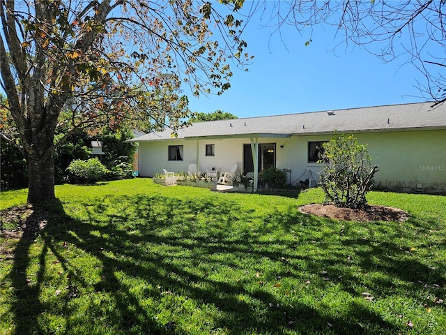 rear view of property with a lawn and stucco siding