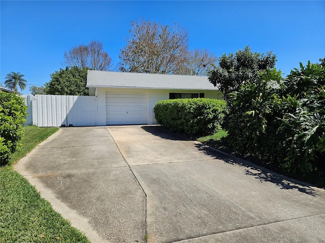 garage with driveway, a gate, and fence