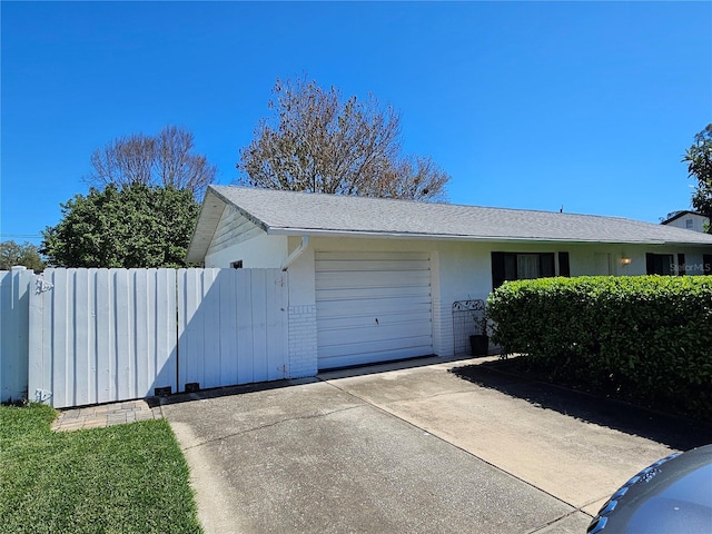 garage with a gate, driveway, and fence