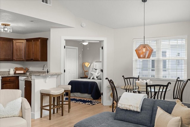 kitchen with light wood-type flooring, open floor plan, vaulted ceiling, and a kitchen bar