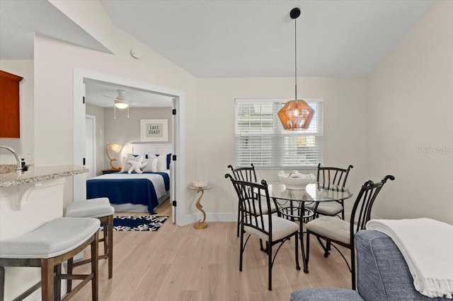 dining room with a ceiling fan, lofted ceiling, light wood-style flooring, and baseboards