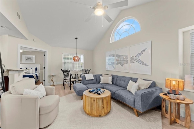 living room with high vaulted ceiling, visible vents, baseboards, a ceiling fan, and light wood finished floors