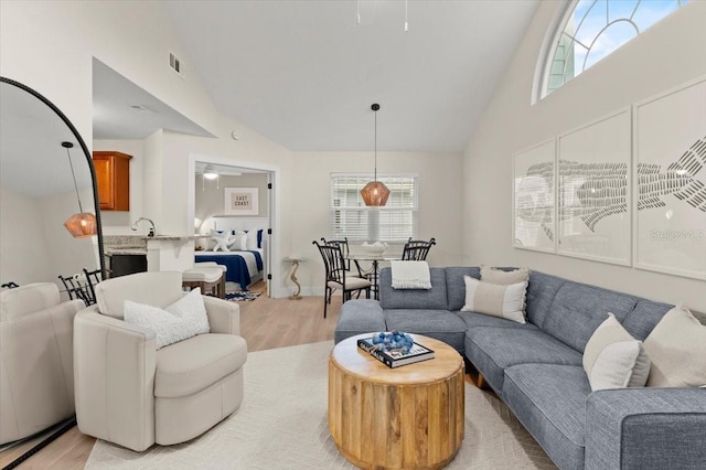 living area with light wood-style flooring, visible vents, high vaulted ceiling, and ceiling fan