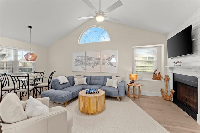 living room with light wood-style floors, a fireplace, a ceiling fan, and a wealth of natural light