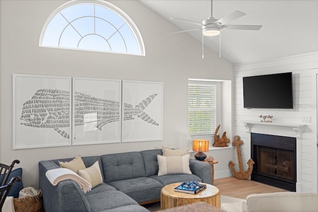 living room featuring lofted ceiling, a large fireplace, ceiling fan, and wood finished floors