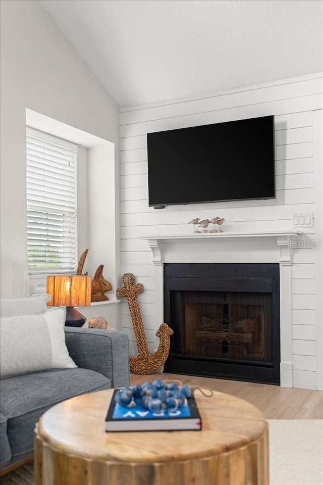 living area featuring vaulted ceiling, a fireplace, and wood finished floors