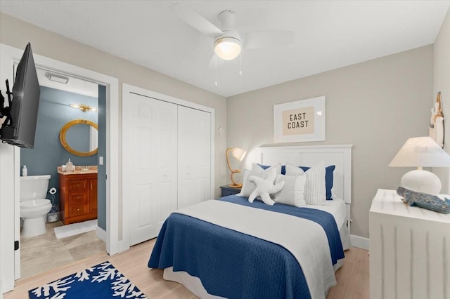 bedroom featuring a closet, ceiling fan, ensuite bath, light wood-type flooring, and baseboards