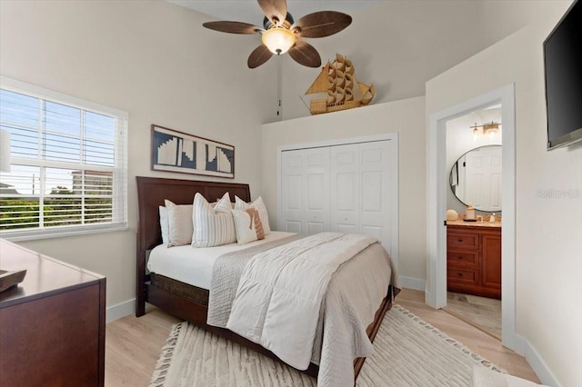 bedroom with baseboards, ceiling fan, ensuite bathroom, light wood-style floors, and a closet