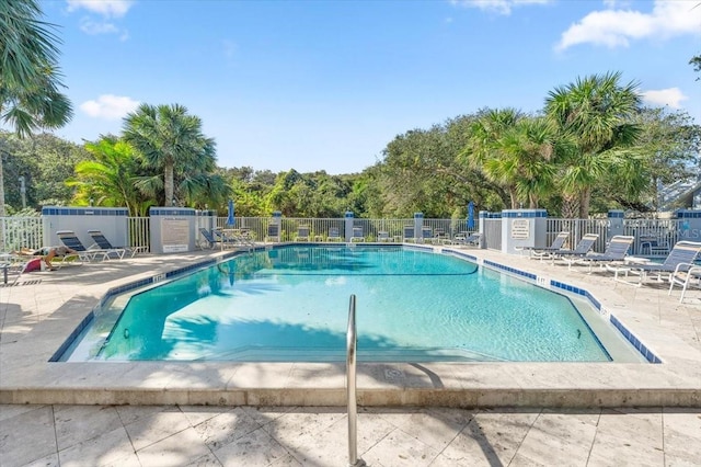 community pool with a patio area and fence