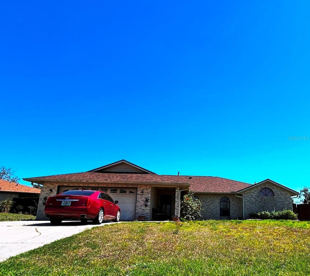 ranch-style house with a garage, a front lawn, concrete driveway, and brick siding