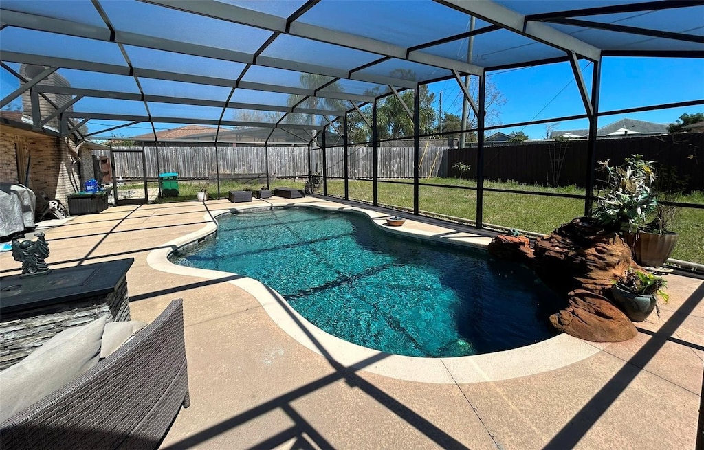 view of swimming pool with a patio, a fenced backyard, a lanai, a lawn, and a fenced in pool