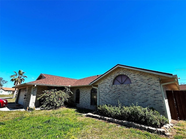 ranch-style house with brick siding, an attached garage, fence, and a front yard