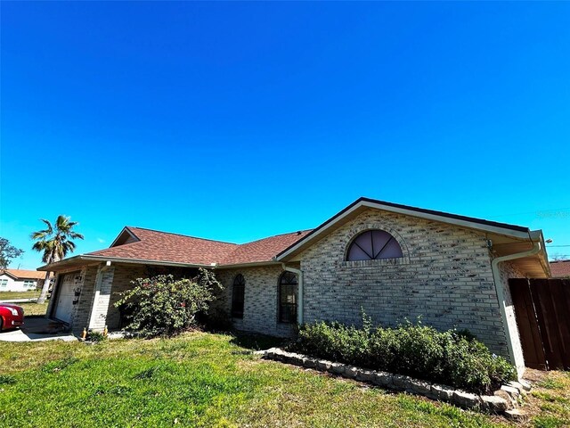 single story home with brick siding, an attached garage, a front lawn, and fence