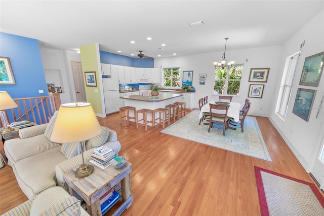 dining area featuring light wood finished floors, baseboards, a notable chandelier, and recessed lighting