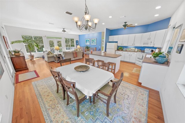 dining area with light wood-style floors, recessed lighting, visible vents, and ceiling fan with notable chandelier