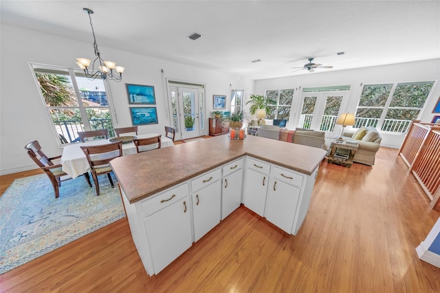 kitchen featuring french doors, light wood finished floors, visible vents, hanging light fixtures, and white cabinetry