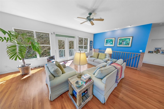 living area with a ceiling fan, baseboards, wood finished floors, and french doors