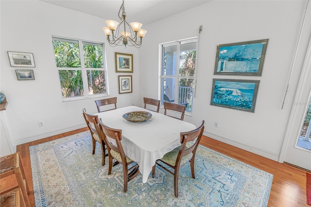 dining space with a chandelier, wood finished floors, and baseboards