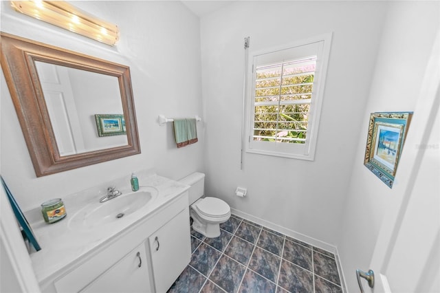 bathroom featuring toilet, vanity, and baseboards