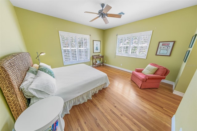 bedroom featuring light wood-type flooring, baseboards, multiple windows, and visible vents