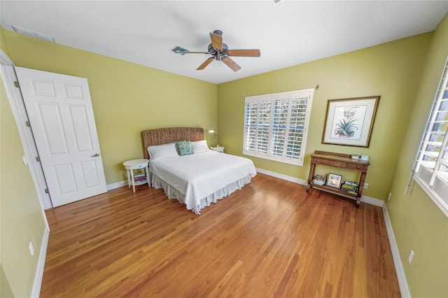 bedroom featuring light wood-style floors, baseboards, visible vents, and a ceiling fan