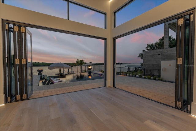 interior space featuring plenty of natural light, a towering ceiling, and wood finished floors