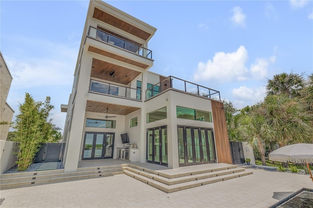 rear view of house with a balcony, fence, a ceiling fan, french doors, and a patio area