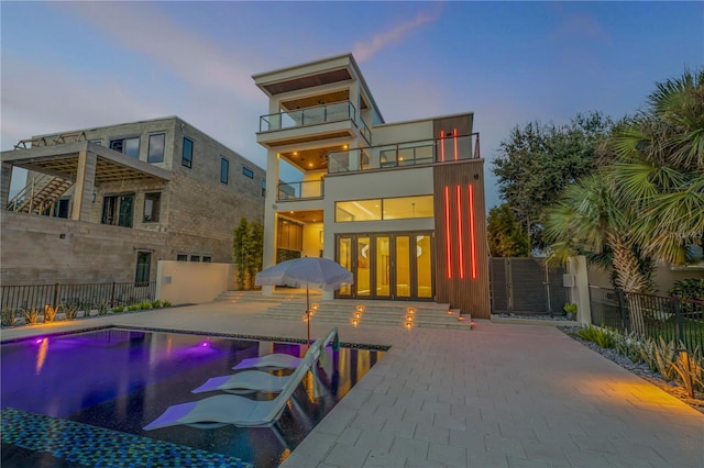 rear view of house featuring a patio area, a fenced backyard, a balcony, and a fenced in pool