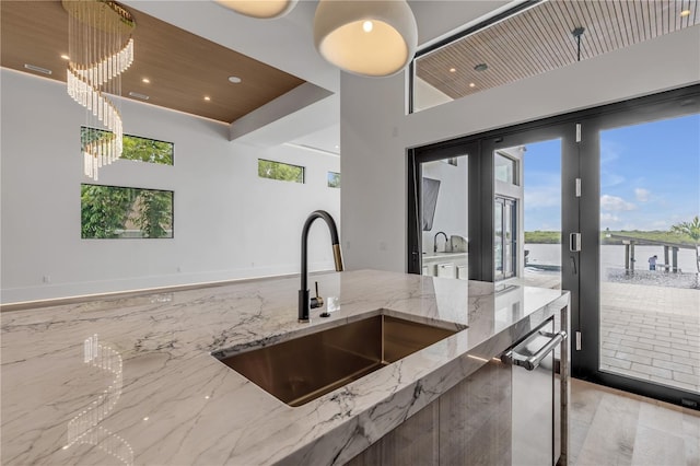 kitchen with wooden ceiling, decorative light fixtures, light stone countertops, french doors, and a sink