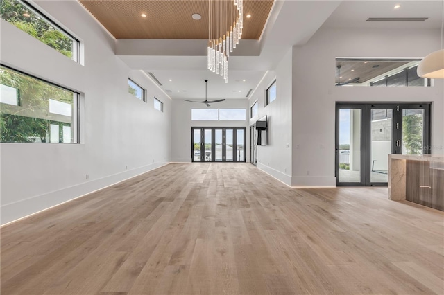 unfurnished living room with recessed lighting, a high ceiling, visible vents, baseboards, and light wood-type flooring