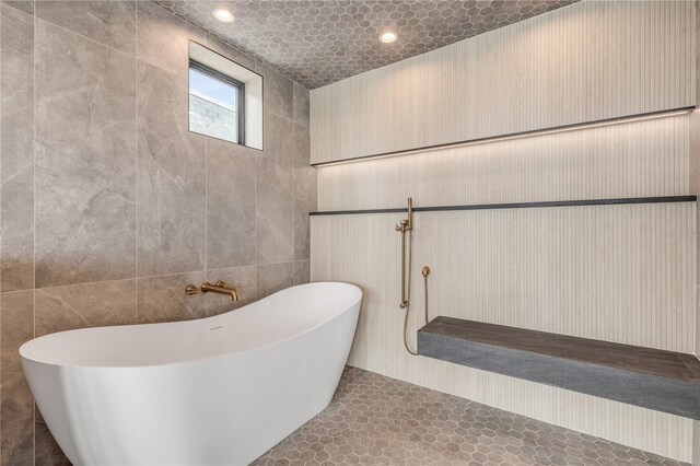 full bathroom featuring recessed lighting, a freestanding bath, and tile walls