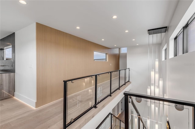 hallway featuring baseboards, wood finished floors, an upstairs landing, and recessed lighting