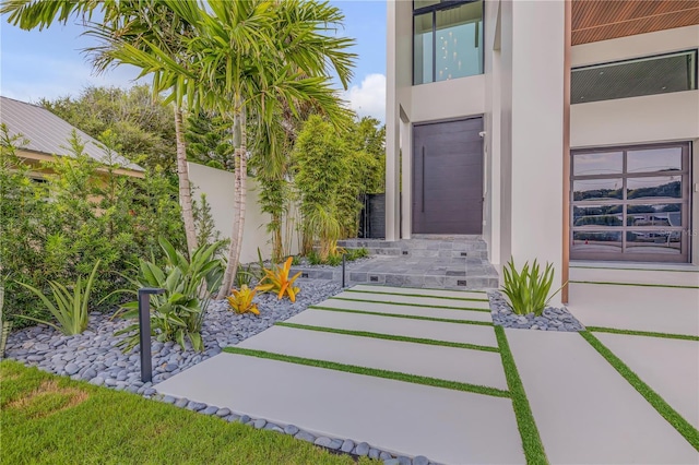entrance to property featuring stucco siding and fence