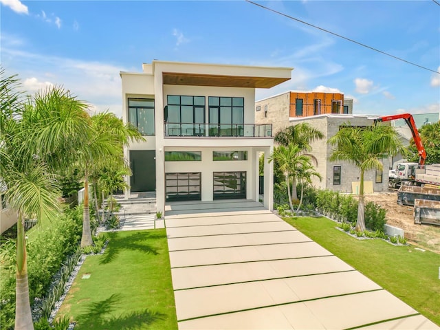 view of front facade featuring a balcony, stucco siding, and a front lawn