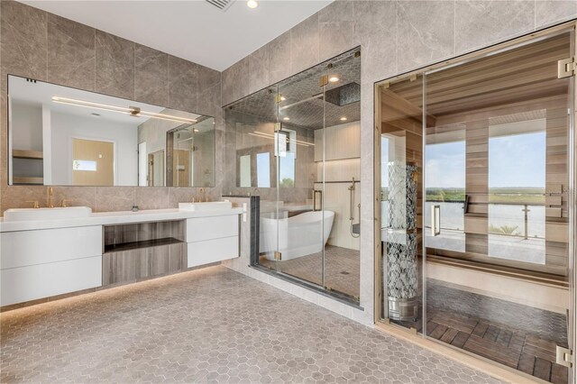 bathroom with tile walls, double vanity, a stall shower, a soaking tub, and a water view