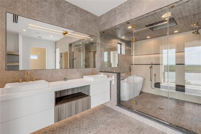 bathroom featuring tile walls, a stall shower, a soaking tub, and double vanity