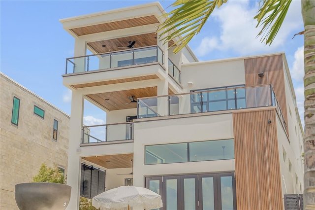 rear view of house with a balcony, stucco siding, and ceiling fan