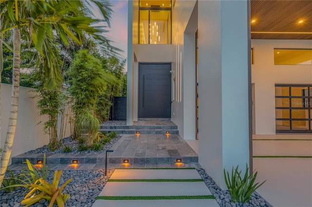 entrance to property with stucco siding and fence