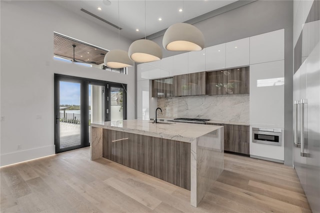 1194 N Peninsula, New Smyrna Beach, FL 32169 - kitchen with modern cabinets, a sink, a towering ceiling, white cabinets, and a center island with sink