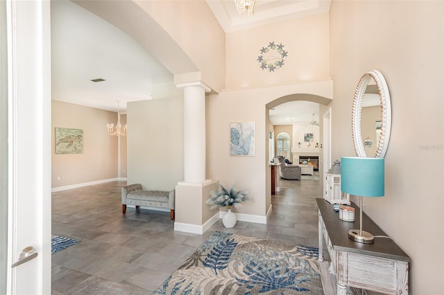 entrance foyer with a glass covered fireplace, a notable chandelier, visible vents, and ornate columns